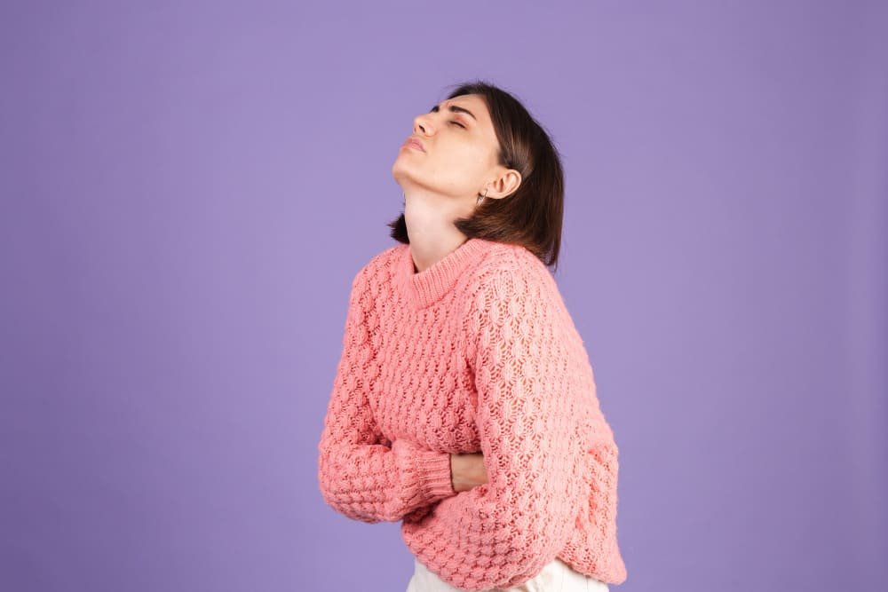 young-brunette-in-pink-sweater-isolated-on-purple-wall